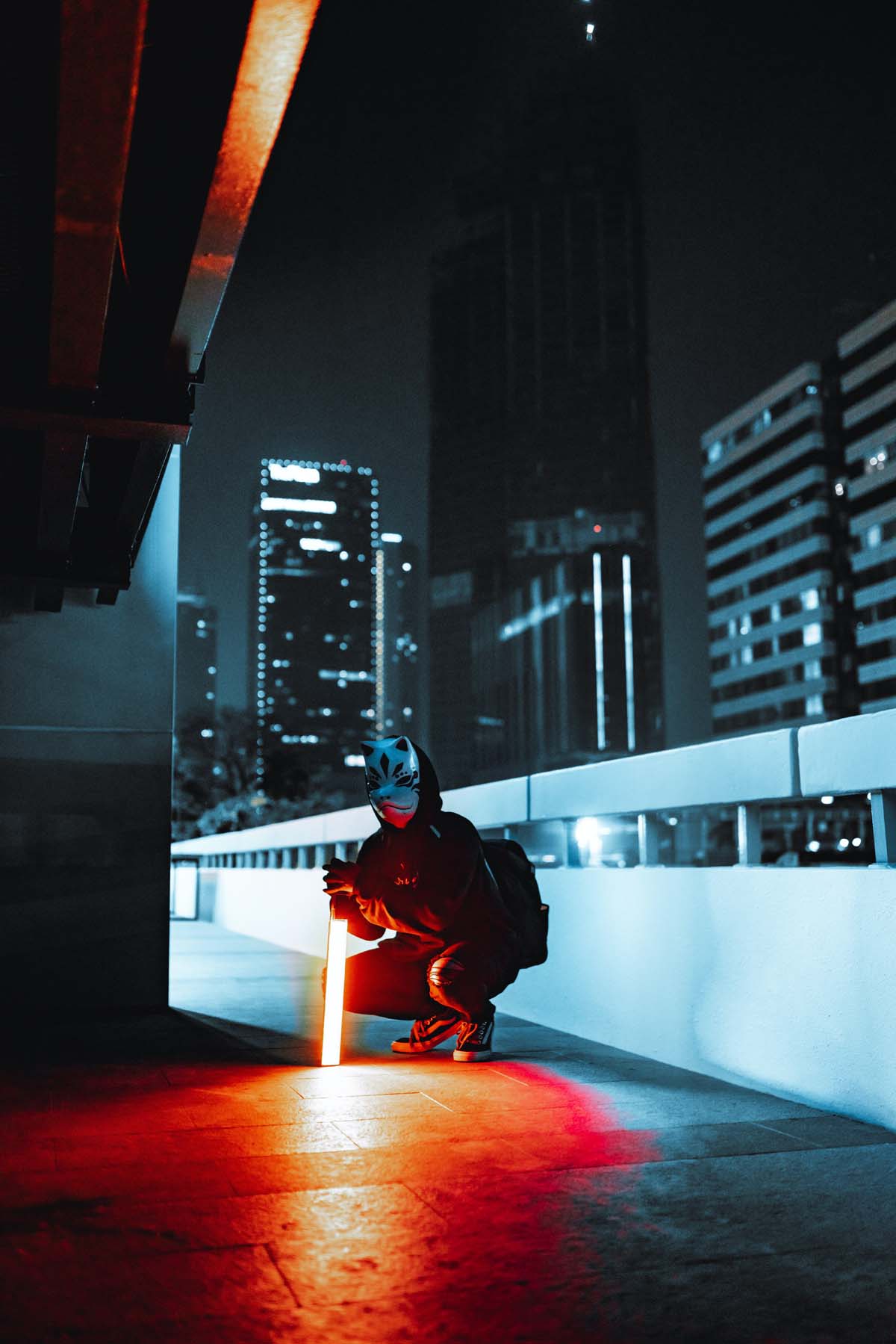 Masked person crouching with light stick